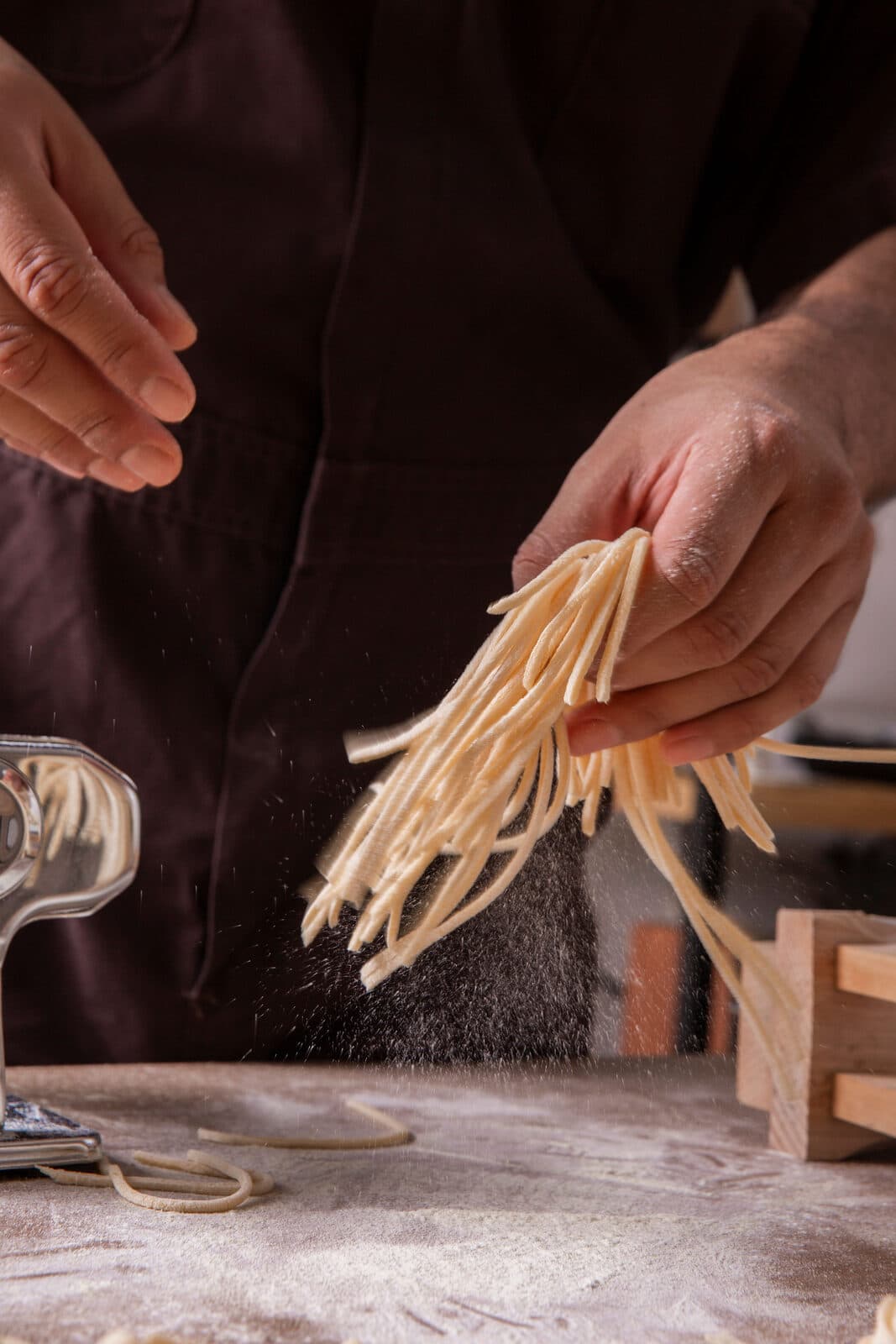 Manos levantando tagliatelle recién cortado en el taller de Parola